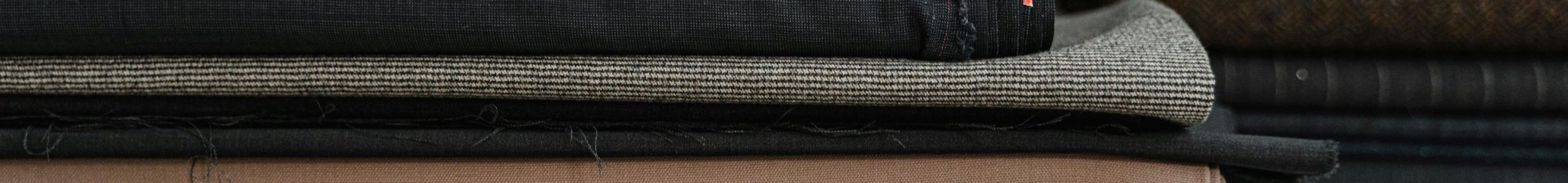 A neatly arranged pile of diverse fabrics, ideal for a fashion designer or tailor's workshop.